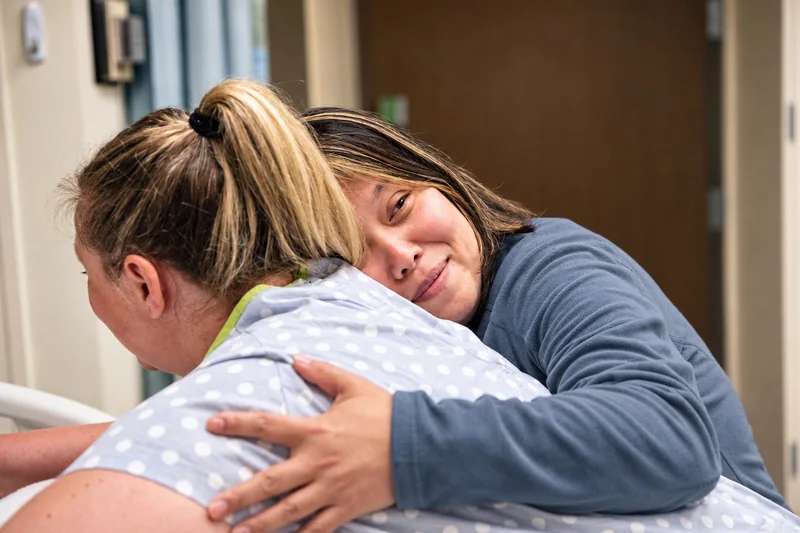 Ellen Hsu embracing a laboring client in a hospital room